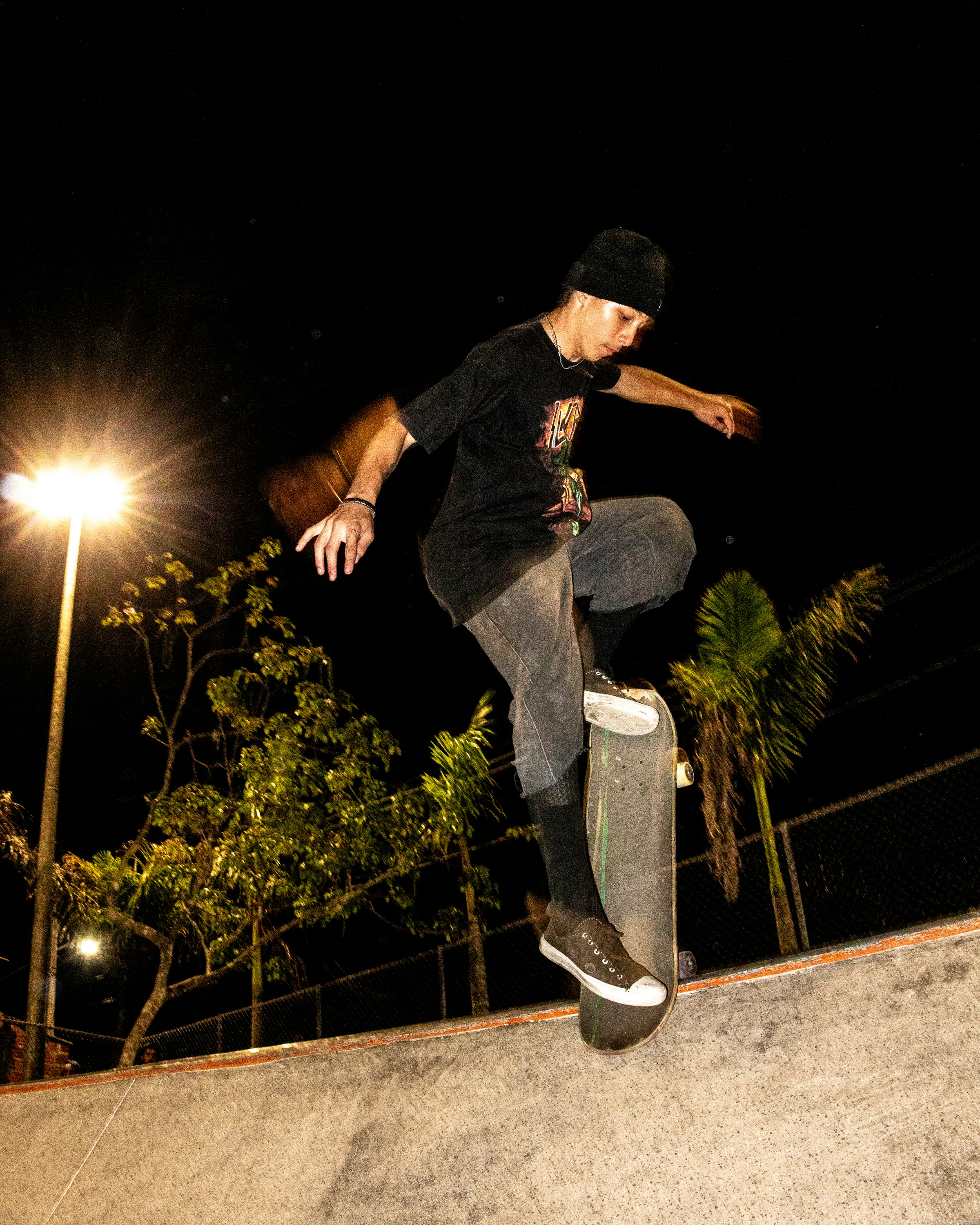A skateboarder performing a trick under a streetlight